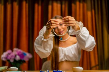 Çok güzel genç bir kadın mücevher hobisi için inci kolye yapıyor.