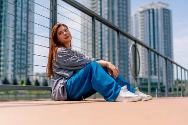 Kızıl saçlı genç bir kızın portresi köprü depresyonu zihinsel bozuklukları üzerine bir şehir manzarasının arka planında.