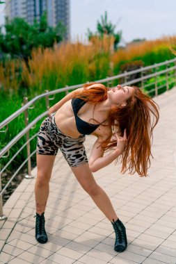 Sokak dansı yapan seksi, formda, topuklu ayakkabı giyen, şehirde dans eden, aktif yaşam tarzı olan genç bir kadın.
