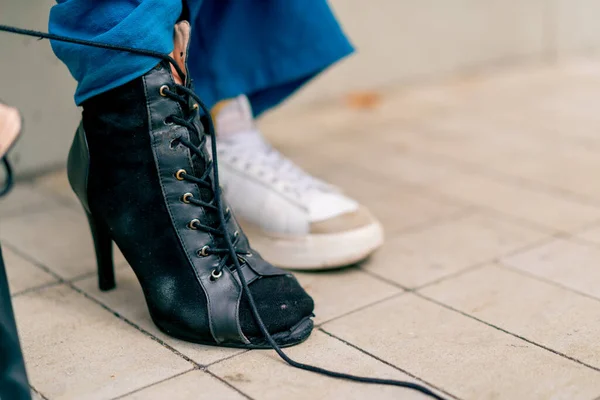 close-up of dancer\'s legs in black high-heeled shoes girl tying shoelaces on street sexuality