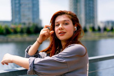 Şehir manzarasının arka planında kızıl saçlı genç bir kızın portresi.