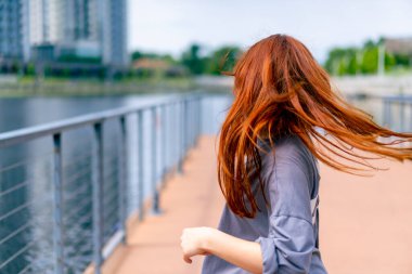 Genç, kızıl saçlı sokak hip-hop dansçısı spor kıyafetleri içinde doğaçlama danslar yapıyor. Bize briç oynuyor. Yoldan geçenlerin ilgisini çekiyor.