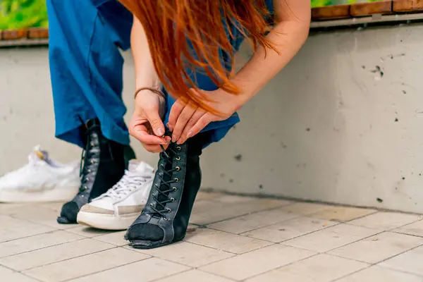 close-up of dancer\'s legs in black high-heeled shoes girl tying shoelaces on street sexuality