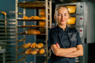 Fırının arka planında ve çeşitli taze hamur işlerinde çalışan profesyonel bir fırıncının portresi.