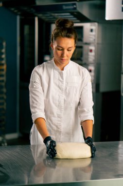 Profesyonel kadın fırıncı sıcak bir fırında taze ekmek pişirmek için hamuru dikkatle yoğurur.