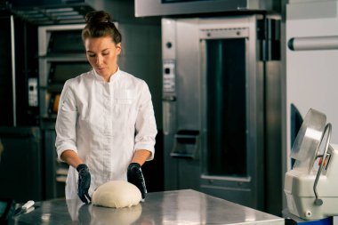 Mutfaktaki profesyonel kadın fırıncı hamuru fırında satılmak üzere mükemmel bir ekmek şekline getiriyor.