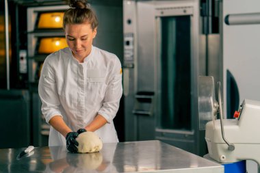 Mutfaktaki profesyonel kadın fırıncı hamuru fırında satılmak üzere mükemmel bir ekmek şekline getiriyor.