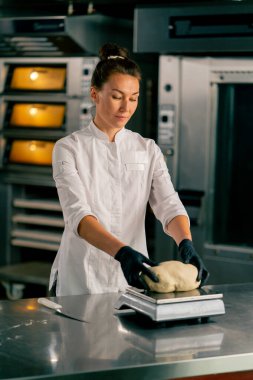 Mutfaktaki profesyonel kadın fırıncı hamuru fırında satılmak üzere mükemmel bir ekmek şekline getiriyor.
