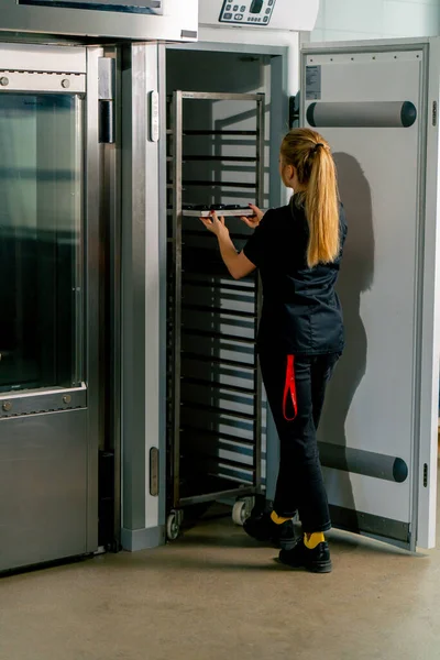 女の子の後ろから撮影 ペストリーシェフは冷蔵庫で硬化するキャンディを置き 冷却温度を設定します — ストック写真