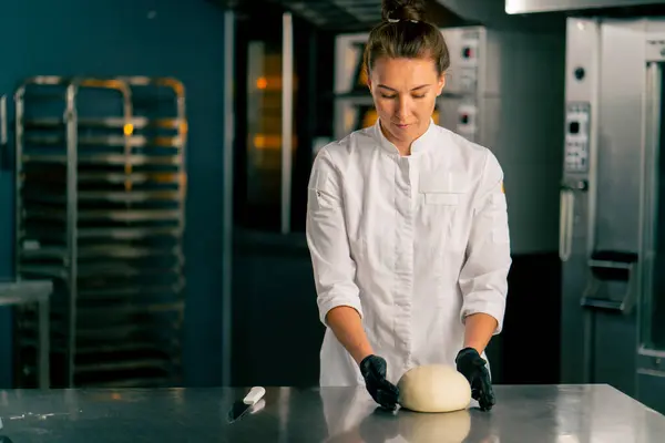 キッチンのプロの女性パン屋はパン屋で販売するための完璧なパンの形に生地を形成します — ストック写真