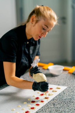 Bir pastacı, pastanedeki bir pastanenin parşömenine doğal şeker şeklinde çikolata sıkıyor.