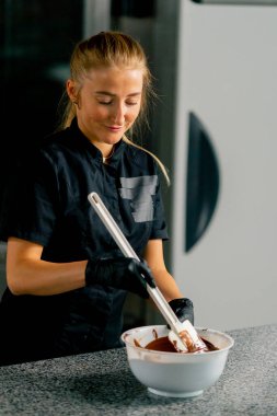 Silikon spatula kullanan kız çikolatacı bir şekerci dükkanında tatlı yapmak için çikolatayı karıştırıyor