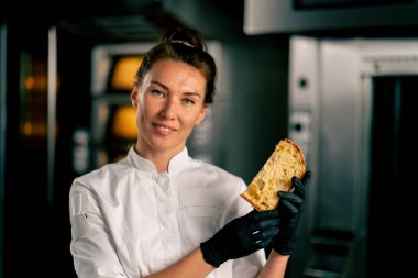 Gülümseyen bir fırıncının portresi elinde taze kesilmiş bir Paskalya somunu kuru kayısı ve bademle kameraya bakıyor.