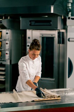 Konsantre kadın fırıncı, kruvasan şekli yaratmak için hamuru eşit parçalara ayırır.