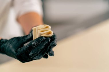 Bir fırında ekmek hazırlamak ve pişirmek için hamuru dikkatle yoğuran bir kadın şefin yakın çekimi.