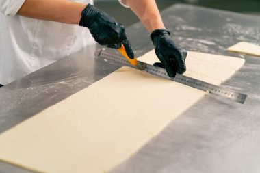 Bir fırında ekmek hazırlamak ve pişirmek için hamuru dikkatle yoğuran bir kadın şefin yakın çekimi.