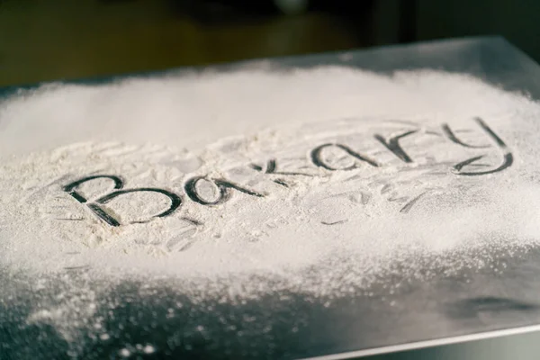 テーブルベーカリーのキッチン表面に小麦粉を含む大きな文字でクリエイティブな碑文 — ストック写真