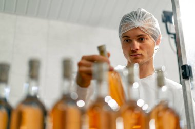 Erkek bir teknoloji uzmanı, üretimdeki şarap şişelerinin ambalaj ve dağıtım sürecini kontrol ediyor.