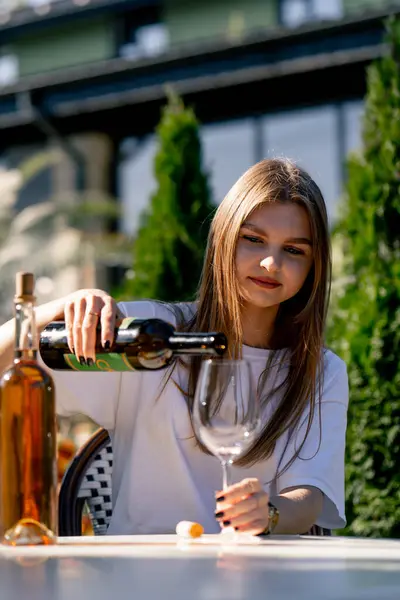 Молодая Красивая Девушка Наливает Вино Бутылки Бокал Сидя Летней Террасе — стоковое фото