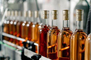 Şarap dolu mühürlü şişelerin yakın çekim görüntüleri mahzendeki depo için şaraphanenin ambalaj hattı boyunca ilerliyor.