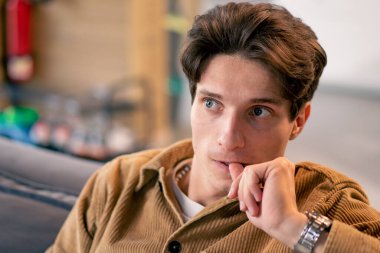 Kanepede oturmuş korku filmi izleyen genç bir çocuğun portresi. İlgi ve tecrübeyle ve elleriyle korkuyla yüzünü kapatıyor.