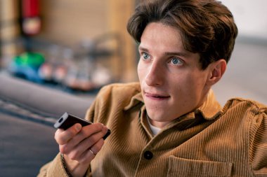 Kanepede oturmuş korku filmi izleyen genç bir çocuğun portresi. İlgi ve tecrübeyle ve elleriyle korkuyla yüzünü kapatıyor.