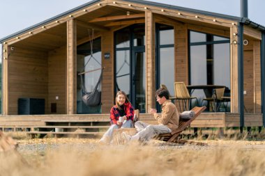 Terasta, büyük bir evin yanında birbirine aşık bir çift, tahta koltuklarda çay içip birbirleriyle iletişim kurarlar.