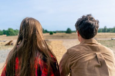 Bir adamla bir kızın, ahşap bir evin terasında oturup bozkırın ve ormanın doğasına hayran kaldıkları bir sahne.