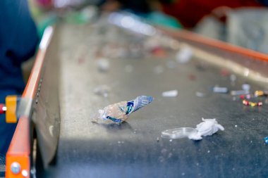 Kullanılmış plastik ve kağıt çöplerinin yakın çekim görüntüleri bir atık geri dönüşüm istasyonunun sıralama hattında yatıyor
