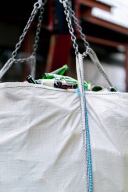 Bir forklift, büyük bir torba dolusu boş cam şişeyi geri dönüşüm için taşır.