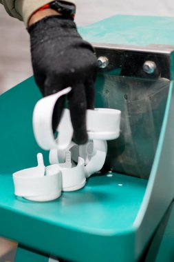 Erkek eli eldivenli yakın çekim. Plastik kapakları geri dönüşüm için öğütme aparatına döküyor.