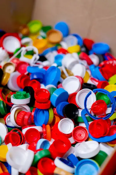 リサイクルおよび廃棄物の分類場所で貯えられる使用されたびんからの多色の帽子のクローズアップ ショット — ストック写真