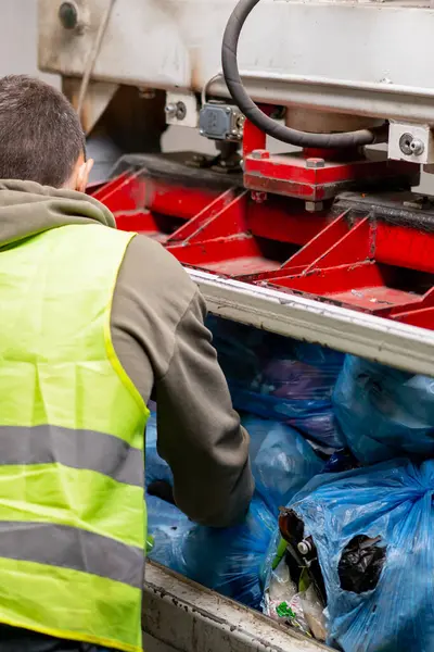 Üniformalı bir geri dönüşüm fabrikası çalışanının arkasından atıklar için özel bir basın makinesine çöp torbaları koyarken vuruldu.