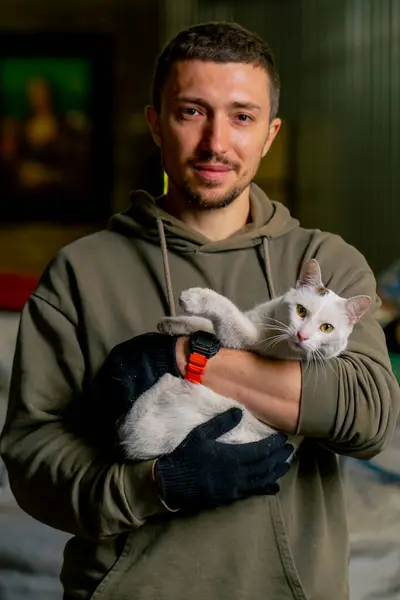 Portrait of a worker at a waste recycling station holding a local beautiful cat in his arms and smiling