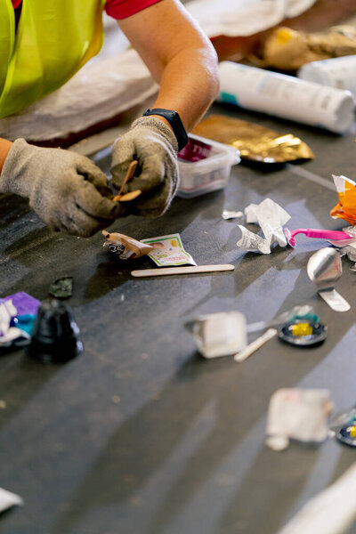 Close-up shot of female hands in work gloves sorting garbage into categories on a special line at a factory