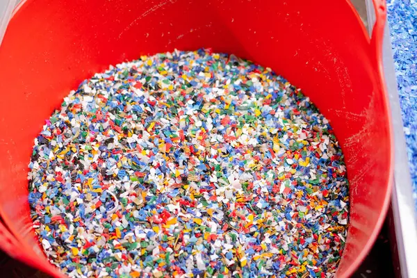 Close-up shot of shredded plastic caps stored in a special container at a waste recycling station