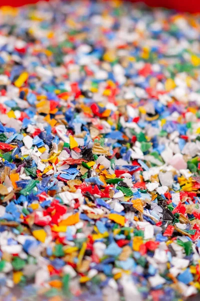 Close-up shot of shredded plastic caps stored in a special container at a waste recycling station
