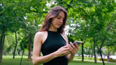 Eğitimden önce ya da sonra parkta yürüyüş yaparken elinde akıllı telefonu tutan aktif, güzel bir Yogi kadını.