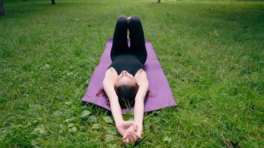 Aktif, güzel Yogi kadın antrenmandan sonra şehir parkında dinleniyor spor paspasına uzanmış gökyüzüne bakıyor.