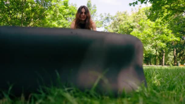 クローズアップ少女は ヨガ瞑想のトレーニングを開始するために公園の草の上にフィットネスマットを表示します — ストック動画