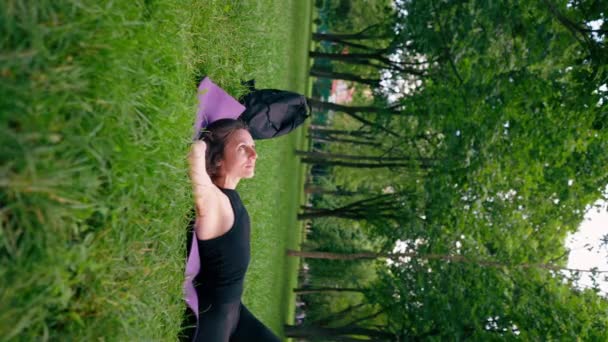 垂直ビデオ アクティブな美しいヨギの女性は 空を見ているフィットネスマットに横たわったトレーニング後に市内公園に休む — ストック動画