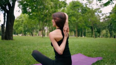 Deneyimli bir kadın eğitmen parkta meditasyon yapar yoga yapar ve farklı kas grupları çalıştırır.