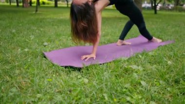 Deneyimli bir kadın eğitmen parkta meditasyon yapar yoga yapar ve farklı kas grupları çalıştırır.