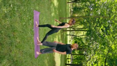 Bir erkek yoga eğitmeni, parktaki bir kadınla birlikte temiz hava ile ilgili bir ders veriyor ve manevi egzersizler yapıyor.
