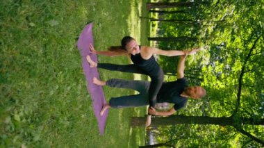 Bir erkek yoga eğitmeni, parktaki bir kadınla birlikte temiz hava ile ilgili bir ders veriyor ve manevi egzersizler yapıyor.