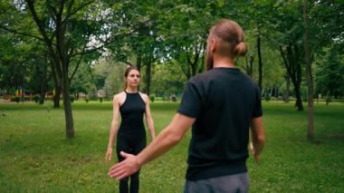 Şehir parkında yoga yapan çift namaste hareketleri ile meditasyon egzersizleri yapıyor. İnsanlar zihinsel ve ruhsal sağlığa odaklanıyor.