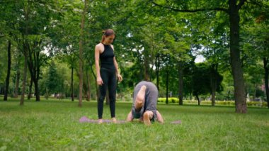 aşık çiftler ya da yoga hocası ve kadın şehir parkında egzersiz yapıyorlar.