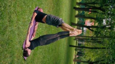 Asana Parkı 'nda egzersiz yapan aşık çift ya da yoga eğitmeni ve kadın sağlıklı vücut germe kasları destekliyor.