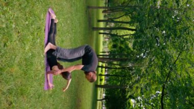 Erkek bir yoga eğitmeni, parkta bir kadınla birlikte temiz hava egzersizi yapıyor. Manevi uygulamalar yapıyor.