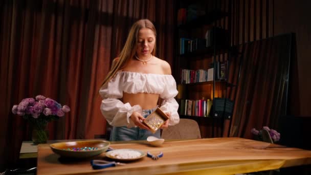 女性デザイナーのニードルウーマンは クリエイティブなクラフトジュエリーネックレスエンゲージメントリングイヤリングブレスレットを作成するために さまざまなビーズの箱をポーズします — ストック動画